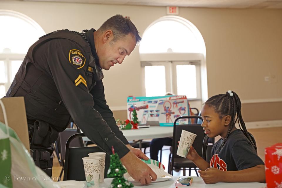 Cpl. Jeff Smith helps his new friend wrap her gifts after participating in the Talbot Optimist's 'Shop with a Cop' event.