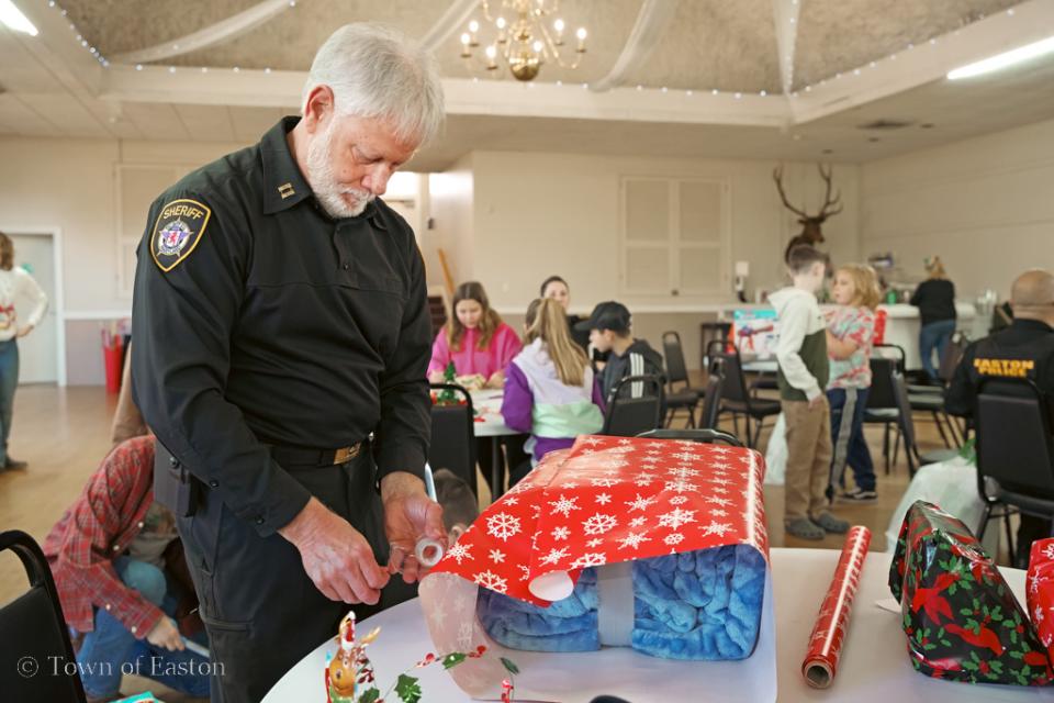 Capt. Bollinger stays focused on wrapping a present during the 'Shop with a Cop' event.